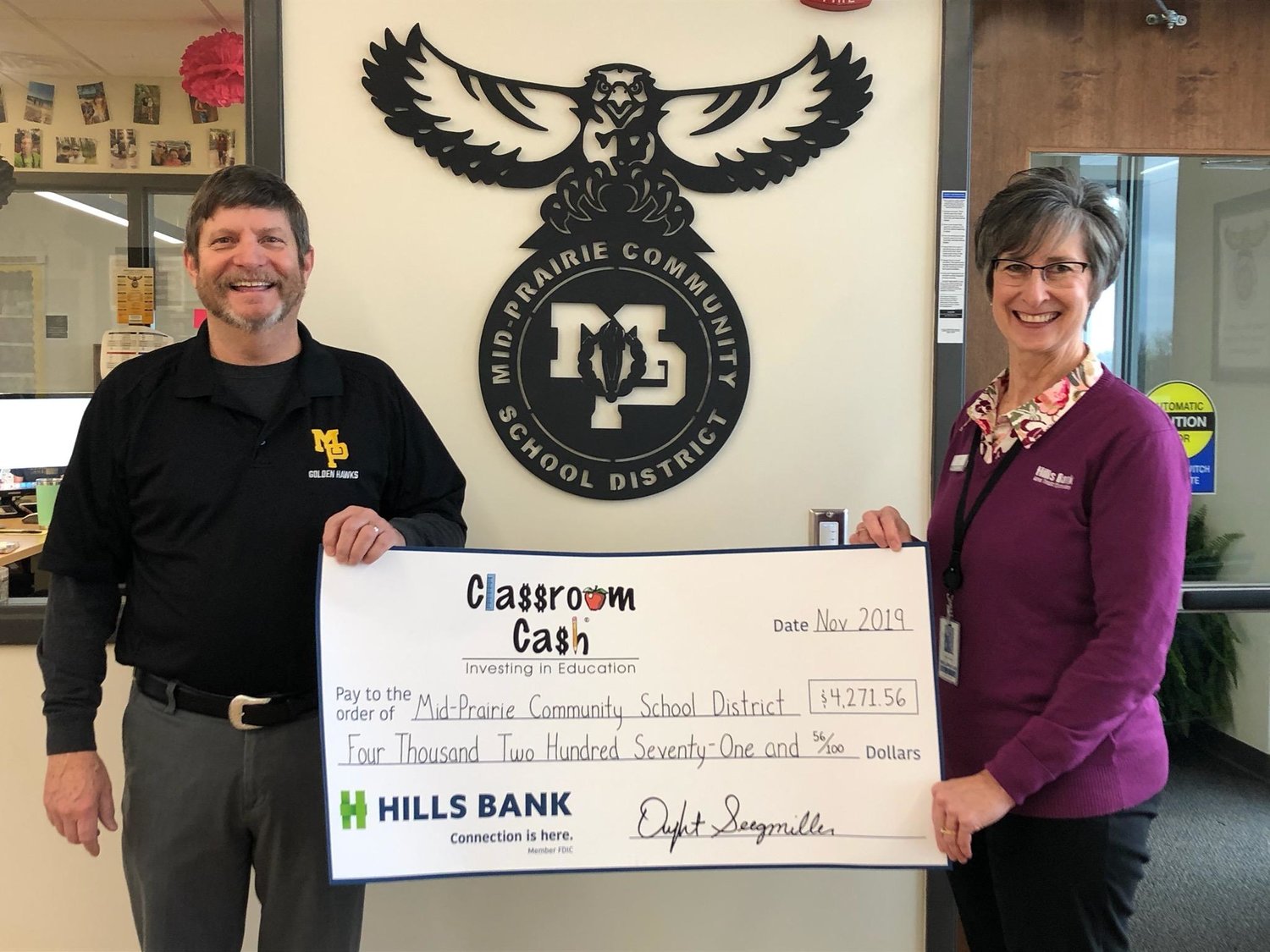 Kris Burns (right) from Hills Bank presents Mid-Prairie Superintendent Mark Schneider with a Classroom Cash check for $4,271.56. These funds will be used for staff professional development.